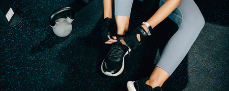 Close-up of a womans legs as she ties her shoelaces before starting her exercise routine. The shot is perfect for fitness and health concepts.の写真素材