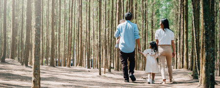 A smiling family of four walking hand in hand through a beautiful park in the summer, Happy family dayの写真素材