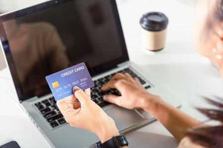 Online shopping. Woman hands holding credit card and using laptop with product purchase at home,...