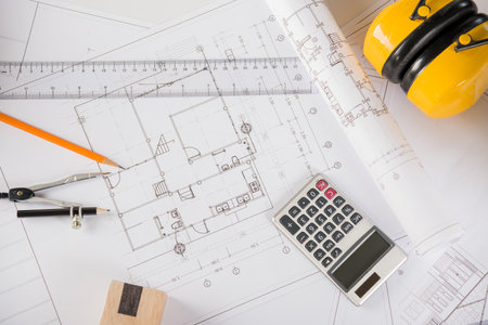 Architectural project workplace. Top view of house plan blueprint paper with repair tools on table desk at architecture office, Engineering architect design tools conceptの写真素材