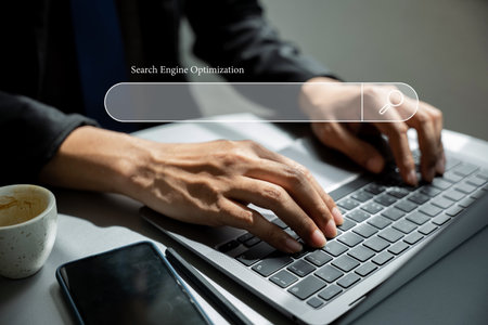 Using a blank search bar, a businessman is browsing the internet and searching for information on his laptop. This stock photo portrays the concept of search engine optimization and networking.の写真素材