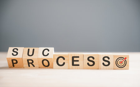 Wooden cube block depicting the journey to success, as it flips over the word process on a wood...