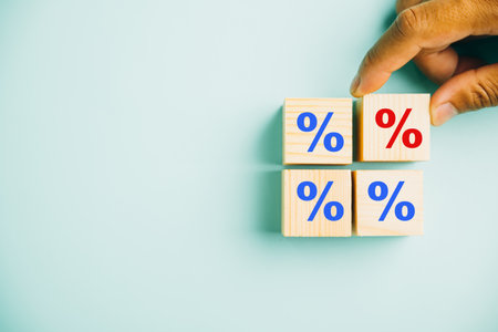 The concept of interest rate and mortgage rates. Businessmans hand positioning a wood cube block with a percentage symbol icon, emphasizing the ever-changing nature of rates.の写真素材