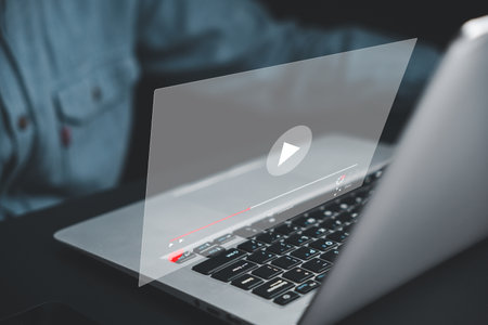 Man immersed in streaming online videos with his laptop. Discover a world of entertainment, education, and inspiration. Embrace the limitless possibilities of digital media.の写真素材