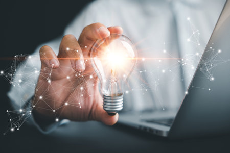 Creative businessman holds a light bulb, representing a bright idea. Showcases the concept of innovation, imagination, and successful profit in global business.の写真素材