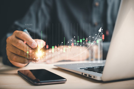 Businessman or trader holds a digital pen, pointing to a growing virtual hologram stock on a...