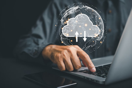 Working amidst data center and big data storage, a computer engineer uses a laptop computer to...