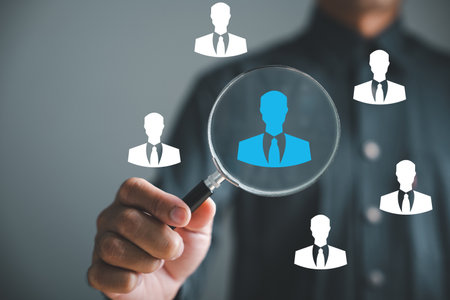 HRM excellence Magnifier glass focuses on manager icon among staff icons, showcasing effectiveness of human resource management in recruitment, leadership, employee development. employees selectionの写真素材