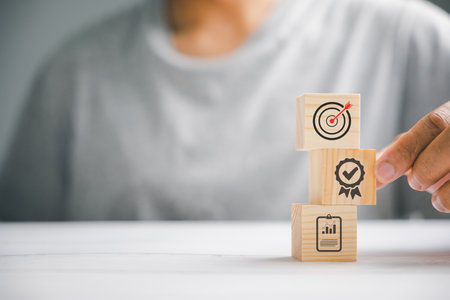 Hand arranging wood blocks to create a strategic stack, aiming for business goals. Conceptual image of business development and success.の写真素材