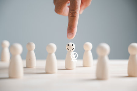 Wooden human figure held by man hand. HR officer looks for leader and CEO. Leader steps out of crowd. Personal development, motivation, challenge. HR, HRM, HRD concepts. Human Resource Management.の写真素材