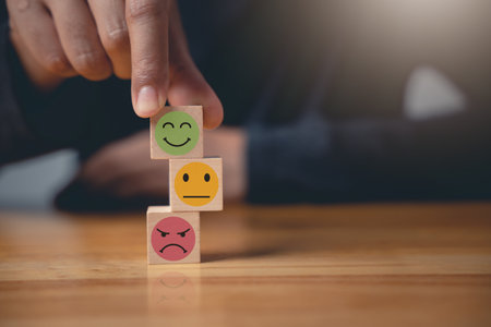The businessman selects a smiley face on a wooden block to rate the quality of excellent business services. Satisfaction survey and feedback concept. 5-star satisfaction is guaranteed.の写真素材