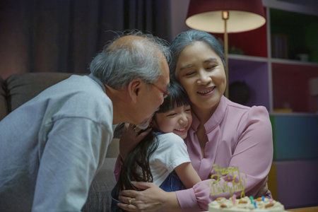 Happy Birthday. Family grandfather and grandmother hugging granddaughter feeling thankful while...