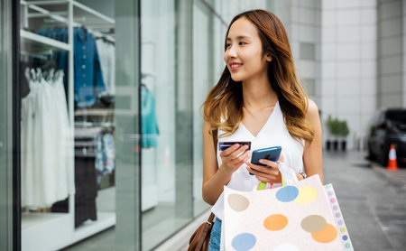 Technology and consumerism collide ,young woman using her smartphone and credit card to make...