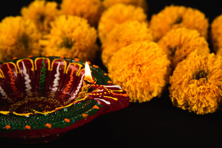Elegant Diwali decor, beautifully crafted Diwali lamp and colorful flower rangoli shining on a striking black background. Ideal for Diwali invitations, religious ceremonies, and cultural celebrationsの写真素材