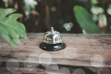 Hotel ring bell. Vintage bell to call staff outdoor in garden with green leaf, Closeup of silver service restaurant bell on wooden counter deskの写真素材