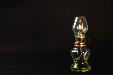 A captivating Diwali concept, An antique oil lamp at night against a black background, radiating a warm, glowing light. Perfect for festive greetings.の写真素材