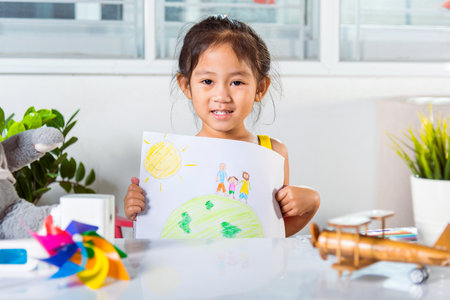 Happy child little girl lift up colorful drawing family standing hold hands on planet earth on paper...