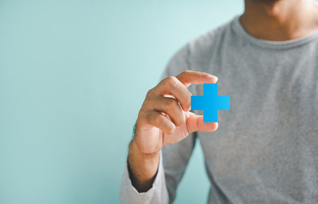 Hands holding plus and healthcare medical icon, symbolizing health insurance concept. Signifies...