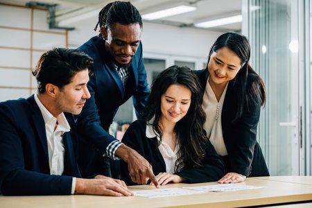 A diverse international team collaborates under female leadership in a meeting room. They discuss financial results, share ideas, and work with documents, demonstrating teamwork and success.の写真素材