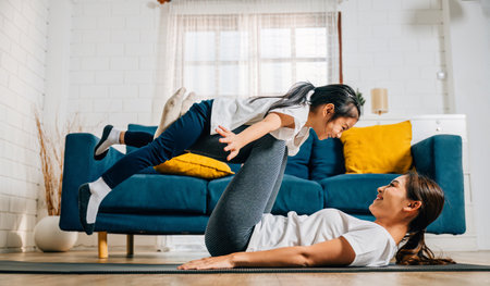 A mother and her daughter find delight in a family yoga moment playfully pretending to fly like airplanes nurturing trust harmony and happiness in their cherished relationship.の写真素材