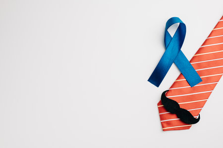 A blue ribbon, embellished with a mustache and necktie, represents Prostate Cancer Awareness and offers support to patients and their families. A symbol of mens healthcare and cancer awareness.の写真素材