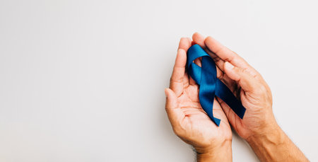 Supporting mens health awareness in November, hands hold a blue ribbon, emphasizing the importance of prostate cancer awareness and support for patients and families.の写真素材