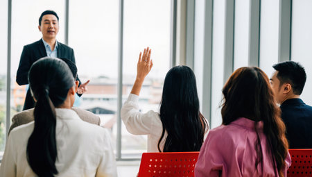 Diverse group of business professionals in seminar meeting room raises their hands reflecting active audience participation and strong sense of teamwork. Its all about question and answer concept.の写真素材