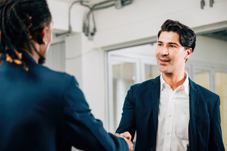 Businessmen and businesswomen shake hands in an office, marking their successful partnership. Colleagues from diverse occupations conclude a productive meeting. Teamworkの写真素材