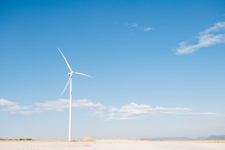 Natures efficiency displayed, windmill farm turbines on a mountain generate clean electricity. A symbol of innovative technology supporting sustainable development under a serene blue sky.の写真素材