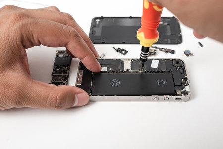 Technician repairing inside the smartphone motherboard with tools for recovery, The man repair by tightening nut from mobile phone with a screwdriver to fix problemの写真素材