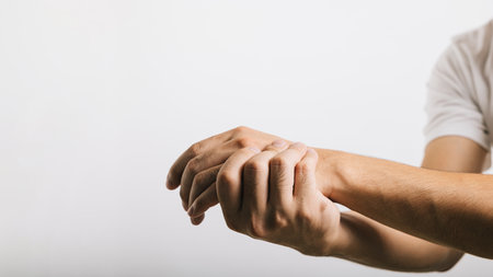 A mans sad portrait, his wrist in pain, possibly due to carpal tunnel syndrome. Studio shot isolated on white background, focusing on health care and the medical concept.の写真素材