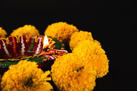 Intricate Diwali lamp and colorful flower rangoli illuminate a captivating black background. Ideal...