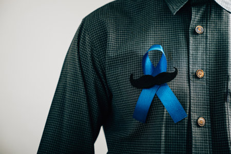 Mens hands exhibit a Blue Ribbon with a moustache, signifying solidarity and support for Colon cancer, Colorectal cancer, Child Abuse awareness, world diabetes day, and International Mens Day.の写真素材