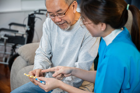 Woman nurse caregiver showing prescription drug to senior man at nursing home, healthcare support, Asian doctor with physician visit senior male patient consult medicine dosage at house in living roomの写真素材