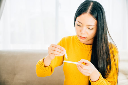 Depicting COVID-19 self-test, Adult female at home unpacks a rapid antigen test kit inserting a swab...