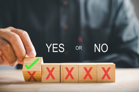 Flipping wooden cube from red cross to correct tick by hand symbolizing project approval concept. Close-up choice change. Think With Yes Or No Choice.の写真素材