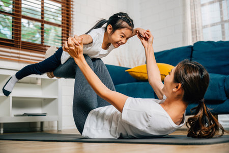 In the comfort of their home a mother and her daughter practice yoga with the little bird posture strengthening their bond and creating a joyful and harmonious family moment of trust and happiness.の写真素材