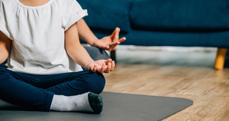 A mother and her daughter find joy in family yoga sitting in lotus position and focusing on mindfulness and meditation creating a harmonious and joyful family moment at home.の写真素材