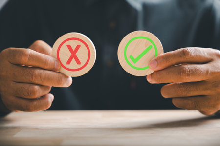Symbolic yes or no, hand holds wooden cubes featuring a green checkmark and red cross. True and...