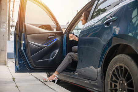 Businesswoman in sleek suit is sitting in modern car. Her long slim leg in high heel shoe opens door exuding elegance and sensuality. Getting out of luxury vehicle is symbol of her glamour and successの写真素材