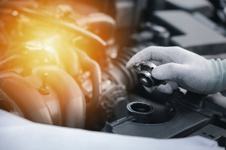 Mechanic working on car engine in garage, checking motor oil level. Horizontal photo of male technician pointing to gauge with frustrated expression. Concept for car servicing and repairing.の写真素材