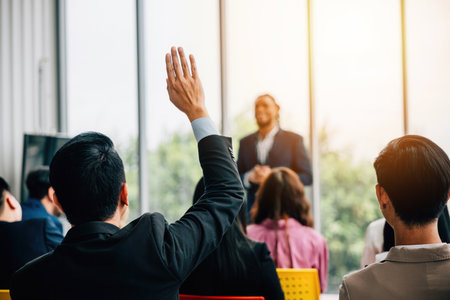 Active engagement during the seminar as attendees raise hands to ask questions emphasizing collaboration teamwork and knowledge-sharing.の写真素材
