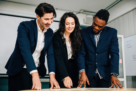 At a conference room desk, business colleagues stand, actively discussing and planning. Teamwork,...