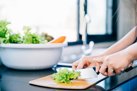 A woman in a blue apron cuts fresh vegetables for a healthy salad in a close-up shot. Illustrating...