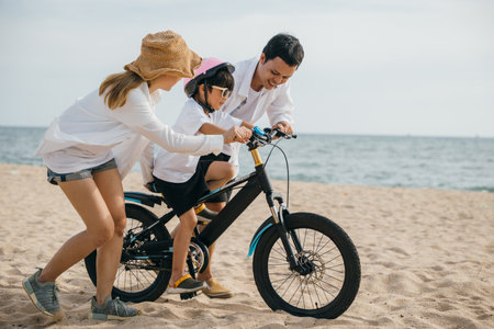 A picturesque sunset scene on sandy beach as parents teach their children joy of bicycle riding...