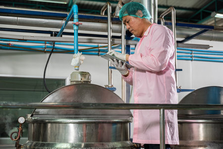 At a beverages factory a worker manages soda water filling with a tablet while an engineer oversees...
