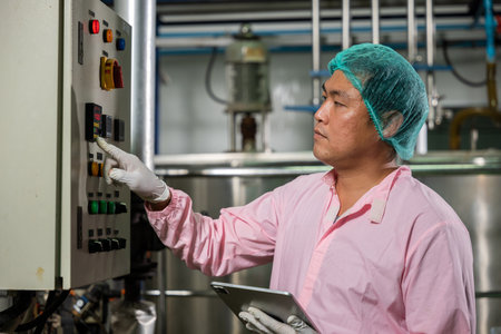 Worker employs tablet in beverage production while an engineer supervises soda water filling....