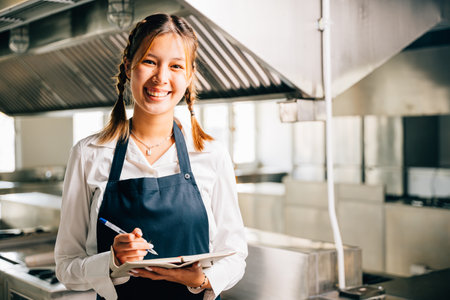 Professional chefs portrait in commercial kitchen. Holding note book pen for teaching. Expertise in education explaining skills. Working confidently presenting ideas to colleagues. Foor educationの写真素材