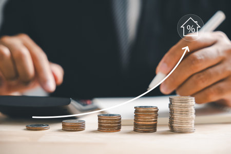 The real estate market upward trend is captured through a graph up arrow. A house model and coin stack convey inflation, economic growth, and insurance service pricing. Property value is ascending.の写真素材