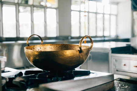 A professional kitchen in a modern restaurant features a shiny metal bowl atop the stove. Clean arrangement of chrome appliances equipment and new furniture. Bright gas service is working.の写真素材